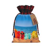 Chanclas en una playa de arena con estampado de lindo color a juego bolsa de Navidad a cuadros diseño de cordón para fiesta de Navidad embalaje de regalo