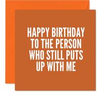 Tarjeta de cumpleaños juguetona con texto en inglés "Still Putting Up with Me", tipografía naranja y blanca con un mensaje de burla, diseño minimalista para una buena risa, cuadrado de 145 mm, sobre